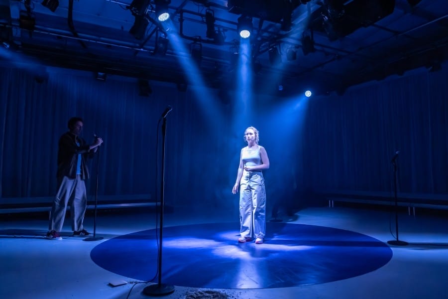 Harriet Gordon-Anderson stands in the centre of a blue circle with spotlights lighting her from above