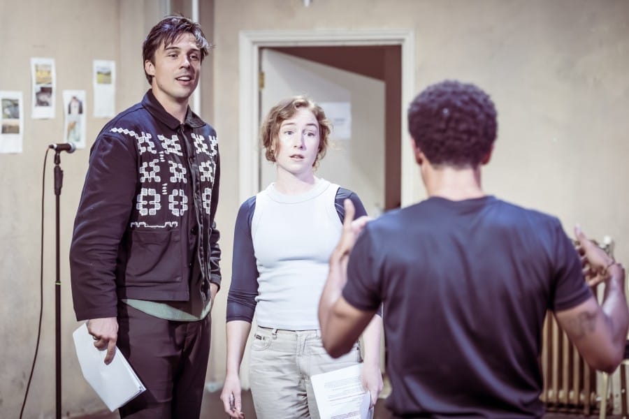 A man and a woman standing next to each other facing a man with his back to the camera