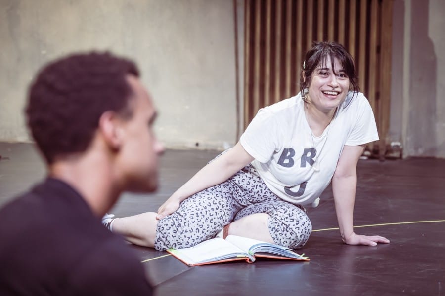 Peyvand, smiling, seated on the floor of the rehearsal room