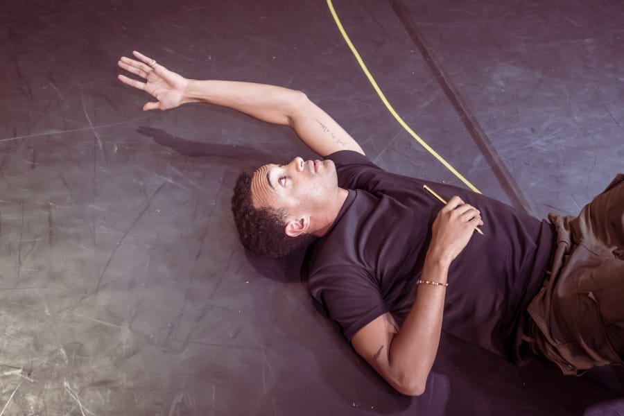 Miles, laid on the floor of the rehearsal room, reaching an arm above his head