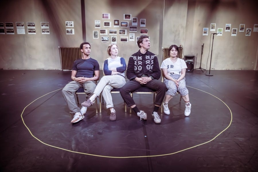 All four actors seated in a row, in the centre of a circle drawn on the floor of the rehearsal room