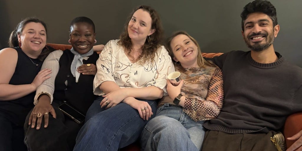 A smiling Gate Team are sitting on a sofa in row